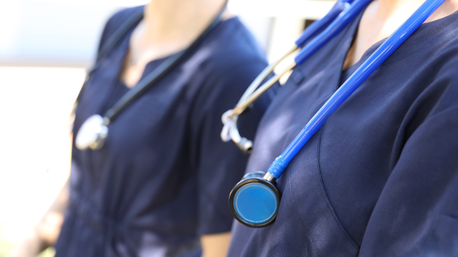 Doctors in navy scrubs with stethoscopes
